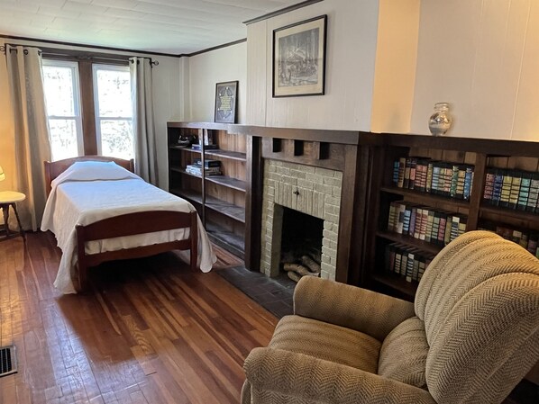 A room with a bed, a fireplace, and bookshelves.