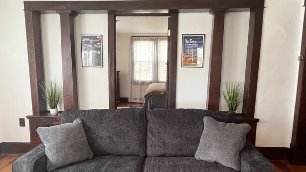 A gray sofa with two cushions in a room with wooden beams and two potted plants.
