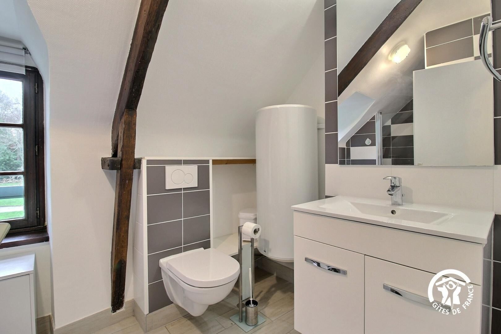 Une salle de bain moderne équipée de toilettes, d’un lavabo et d’un miroir.