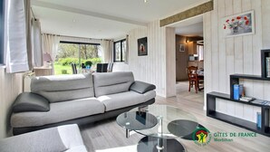 Una sala de estar moderna con un sofá gris, una mesa de centro de vidrio y una estantería.