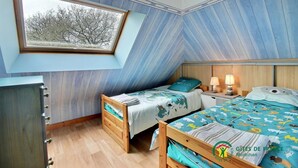 Un dormitorio con dos camas, una ventana y techo inclinado.