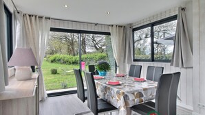 Comedor con una mesa dispuesta para seis personas, ventanas amplias y vista al jardín.