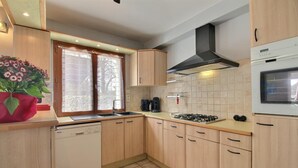 Una cocina moderna con armarios de madera, estufa a gas, horno empotrado y ventana con cortinas.