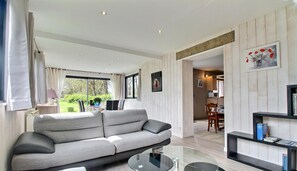 A modern living room with a grey sofa, a glass coffee table, and a bookshelf. - Du Pont Romain - Sarzeau (SARZEAU)