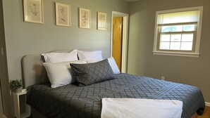 A bedroom with a bed, pillows, a bedside table with a plant, and framed botanical prints on the wall. - Patten Place - Close to everything in Oneonta - clean, updated private home. (Oneonta)