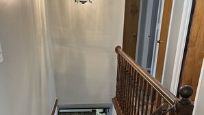 A wooden staircase with a handrail, leading to a landing with a light fixture. - Patten Place - Close to everything in Oneonta - clean, updated private home. (Oneonta)