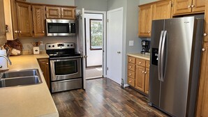 A kitchen with wooden cabinets, stainless steel appliances, a double oven, and a refrigerator. - Patten Place - Close to everything in Oneonta - clean, updated private home. (Oneonta)