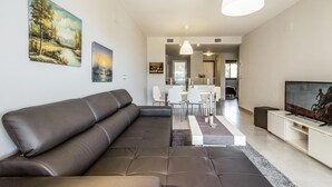 Una sala de estar moderna con sofá, comedor y televisor.