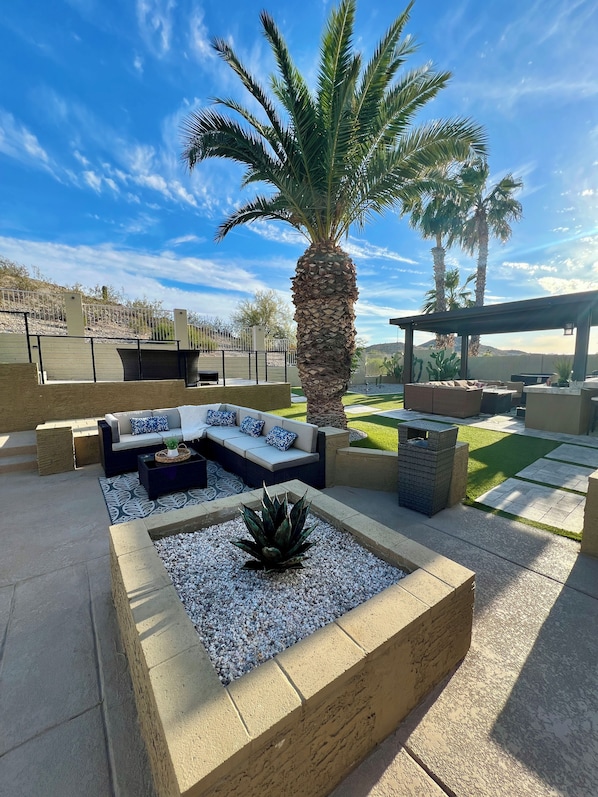 An outdoor patio with a seating area, a palm tree, and a pergola.