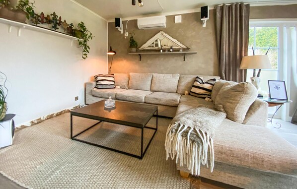A living room with a sectional sofa, a coffee table, a lamp, and a small table with a laptop. - 1 bedroom beautiful home in Skene (Skene)