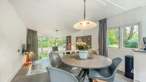 A modern dining area with a round table, grey chairs, and a hanging light fixture.