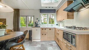 A modern kitchen with a dining area, large windows, and a built-in oven.