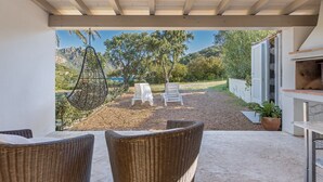 Eine Terrasse im Freien mit Korbmöbeln, einem Hängesessel und Blick auf eine gebirgige Landschaft.