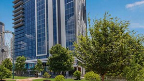 A modern building with a glass facade, surrounded by trees and a Ferris wheel in the background. - 1BD Deluxe/Atlanta Margaritaville - Downtown w/Rooftop Pool and Pool Bar! (Atlanta)