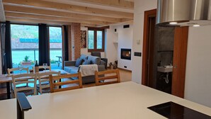 Ein modernes Wohnzimmer mit Kamin, Essbereich und großen Fenstern.