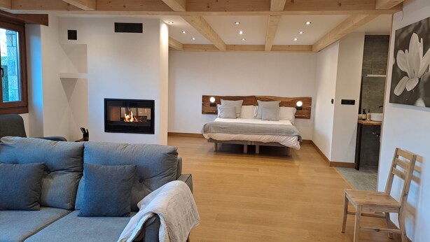 Ein modernes Schlafzimmer mit Kamin, einem großen Bett und einer gemütlichen Sitzecke.