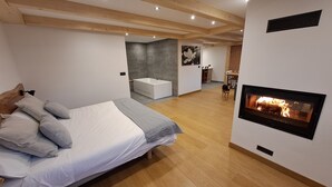 Ein modernes Schlafzimmer mit einem großen Bett, einem Kamin und einem angrenzenden Badezimmer im Hintergrund.