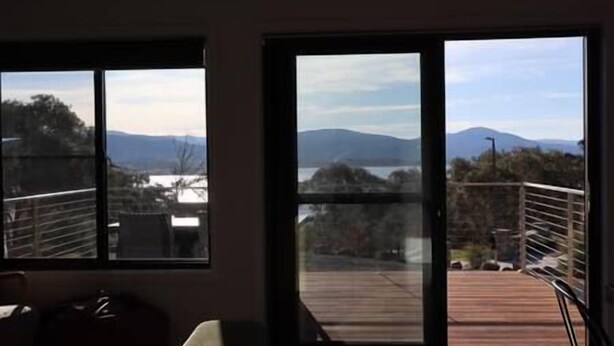 A room with large windows offering a view of a deck and mountains.