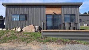 A modern building with a flat roof, large windows, and a wooden deck.