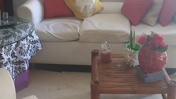 A living room with a white sofa, a wooden coffee table, and a chandelier.