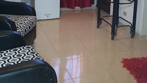 Espaço compacto com cozinha compacta, sofá, mesa pequena e cortina vermelha.