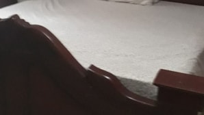 Quarto com cama de madeira, travesseiro branco e ar condicionado fixado na parede.