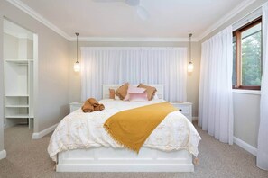 A bedroom with a bed, nightstands, a wardrobe, and a window with curtains.