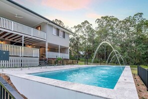 A two-story house with a swimming pool and a fountain.