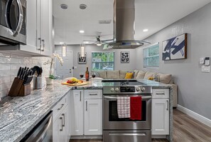 A modern kitchen with a central island, stainless steel appliances, and a seating area with a sofa and cushions. - Great Duplex, 2 Kitchens, Sleeps 12 | 5 Min to Busch Gardens, Tampa (Tampa)