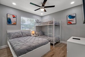 A bedroom with bunk beds, a ceiling fan, a bedside table with a lamp, and artwork on the walls. - Entire Duplex, 2 Kitchens, Sleeps 12 | 5 Min to Busch Gardens, Tampa (Tampa)