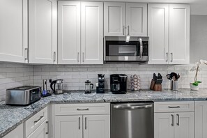 A modern kitchen with white cabinets, stainless steel appliances, and a granite countertop. - Great Duplex, 2 Kitchens, Sleeps 12 | 5 Min to Busch Gardens, Tampa (Tampa)