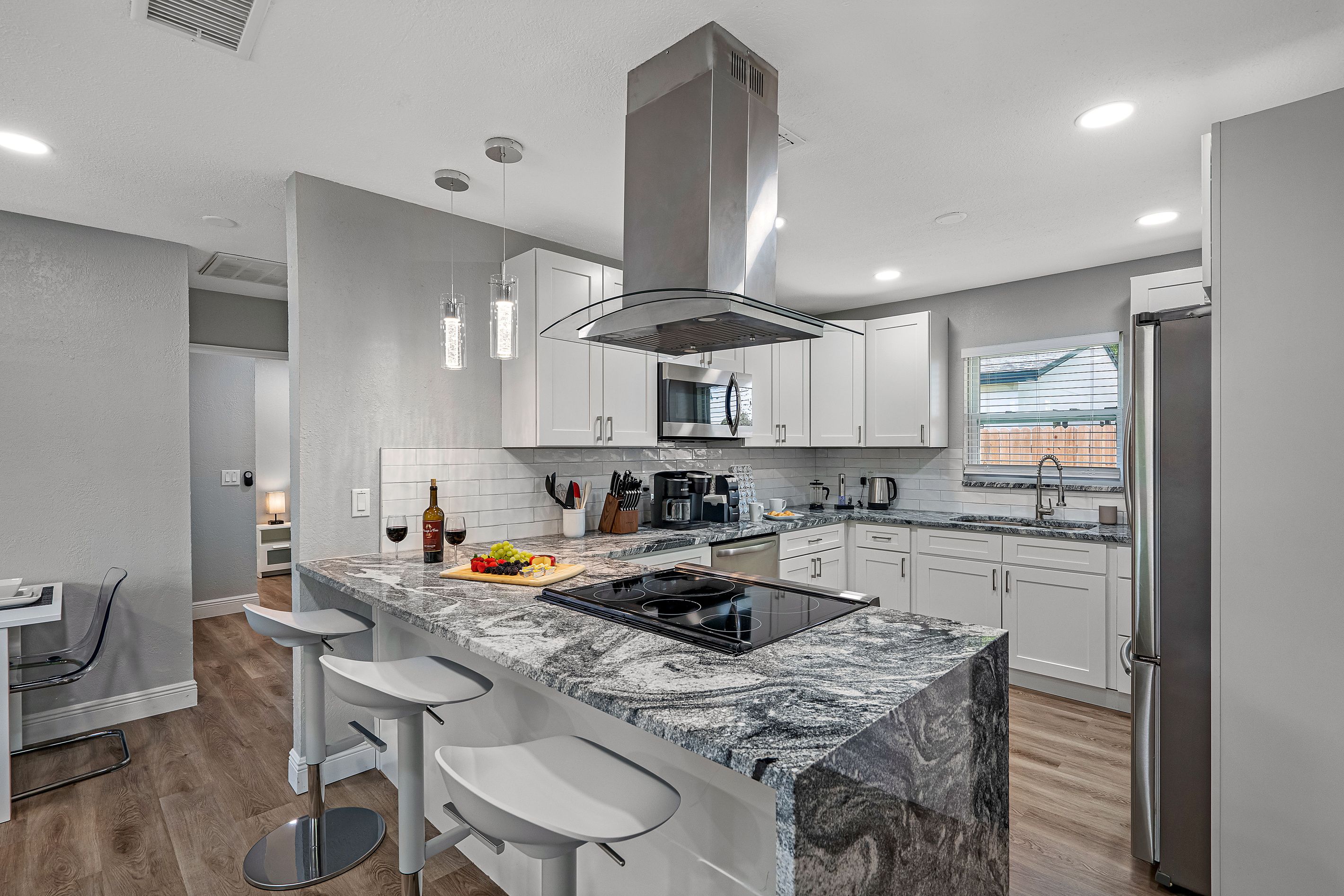 A modern kitchen with a marble countertop, stainless steel appliances, and a built-in oven.
