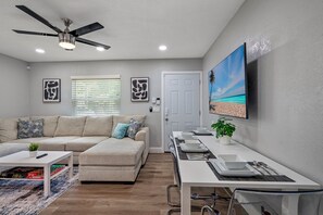 A modern living room with a sofa, coffee table, and a ceiling fan. - Entire Duplex, 2 Kitchens, Sleeps 12 | 5 Min to Busch Gardens, Tampa (Tampa)