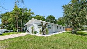 Een gelijkvloers huis met een plat dak, een veranda en een kleine voortuin.