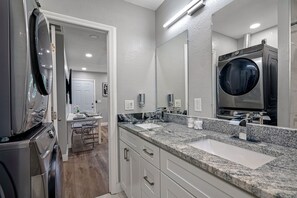 A modern bathroom with a double sink, a large mirror, and a built-in washing machine. - Great Duplex, 2 Kitchens, Sleeps 12 | 5 Min to Busch Gardens, Tampa (Tampa)