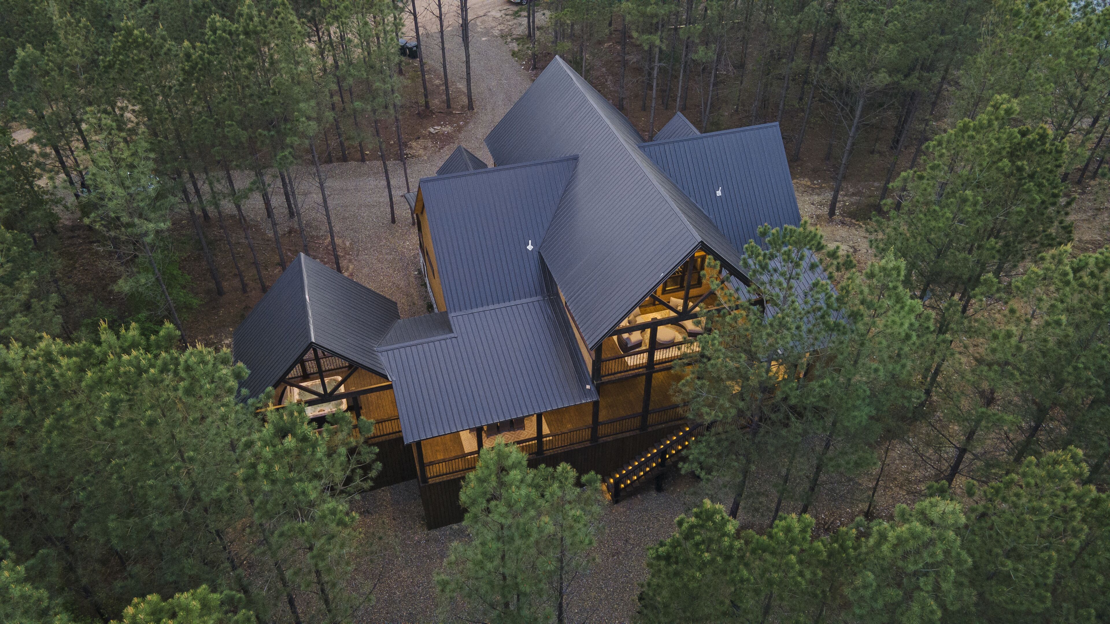 A cabin with a steeply pitched roof surrounded by dense forest.