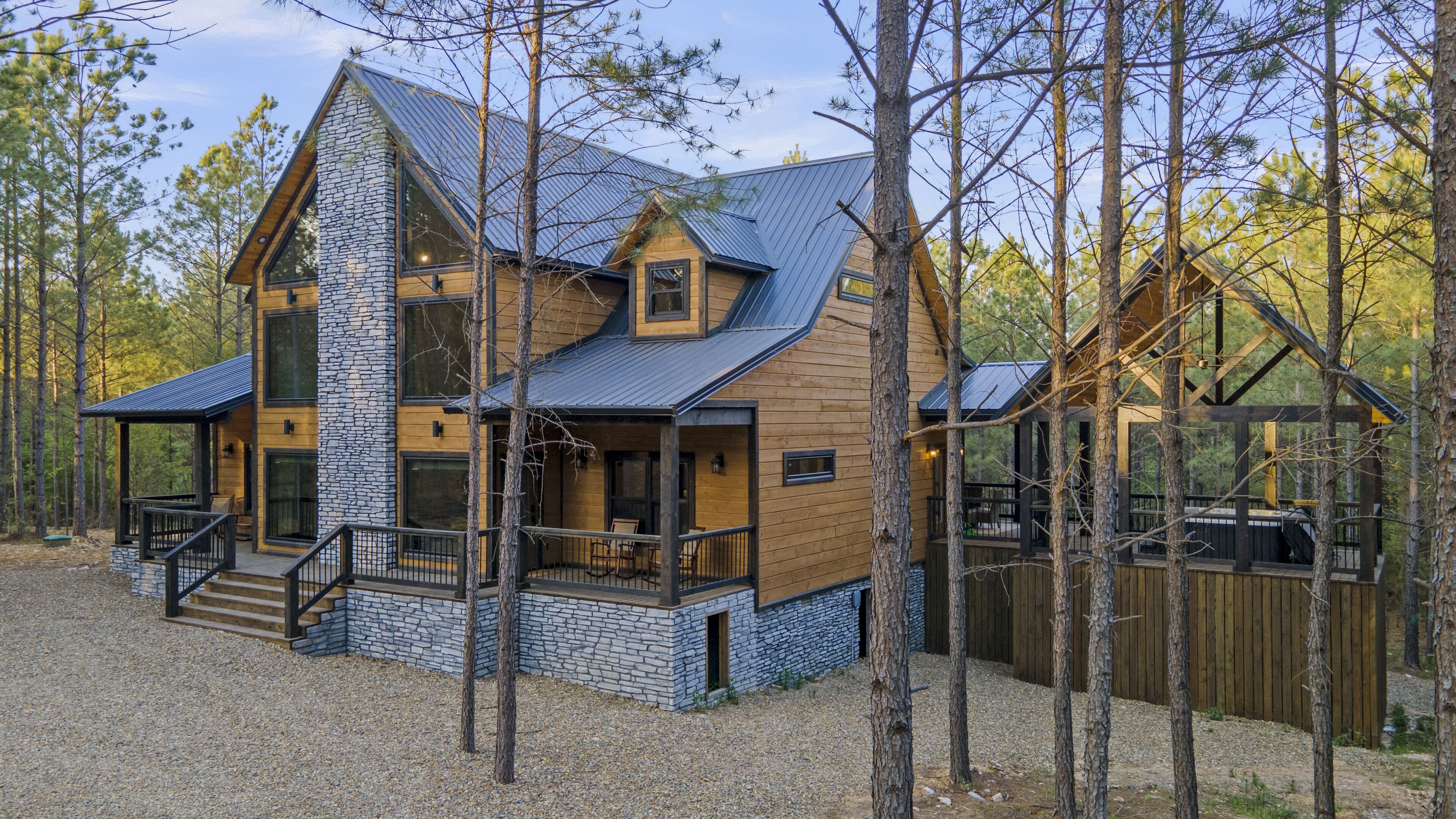 A cabin with a stone facade, wooden exterior, and a porch with outdoor seating.