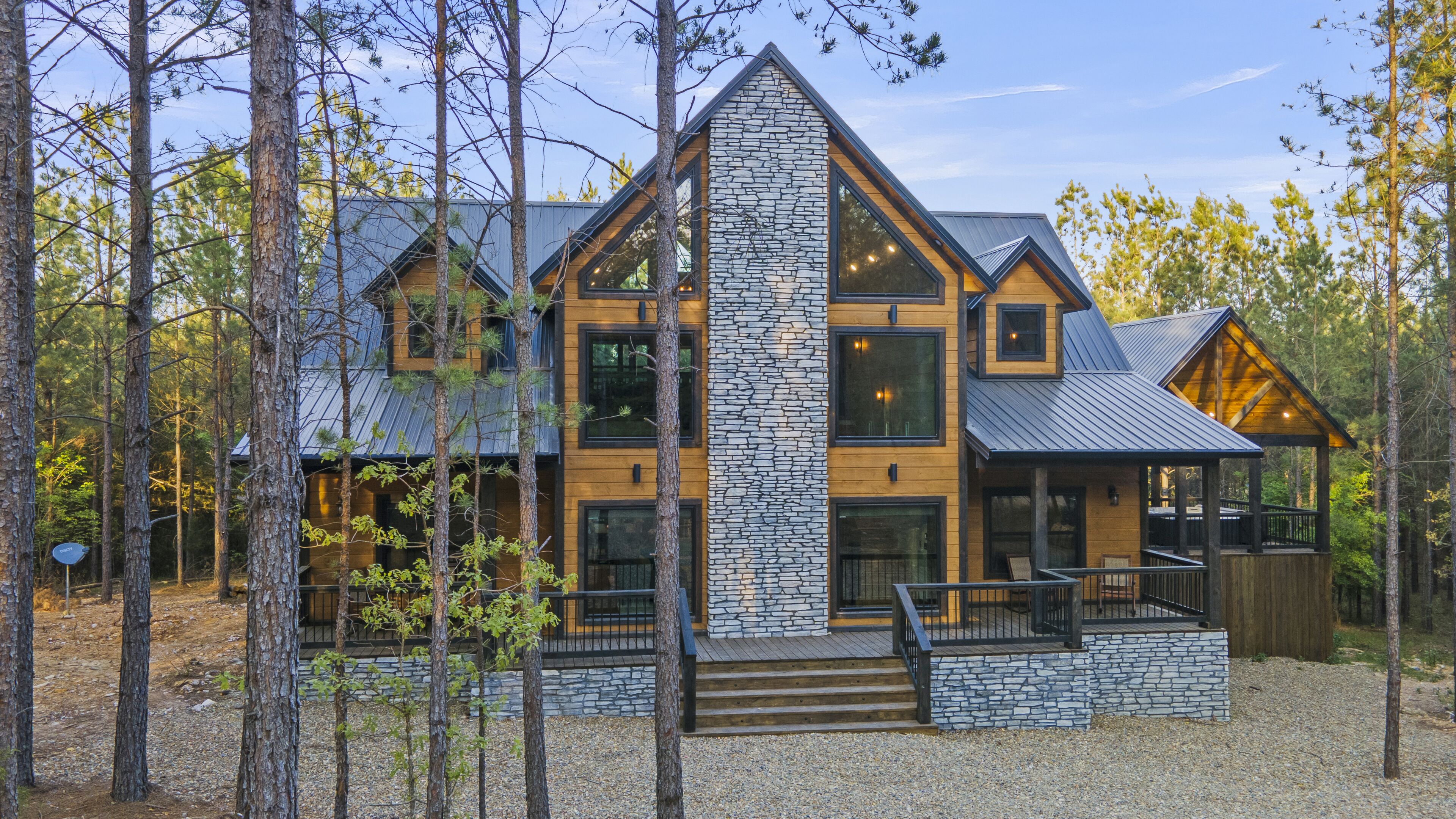 Eine moderne Blockhütte mit Steinverkleidung, mehreren Fenstern und einer Veranda.