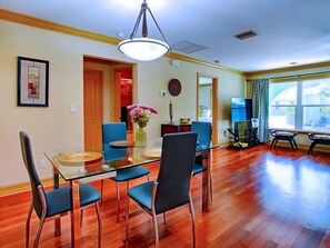 A dining area with a glass table, blue chairs, a vase of flowers, and a clock on the wall. - 30% Disc-2 Kg Mstrs, Golf, Fishing, BBQ, Pool, Spa (Cape Coral)