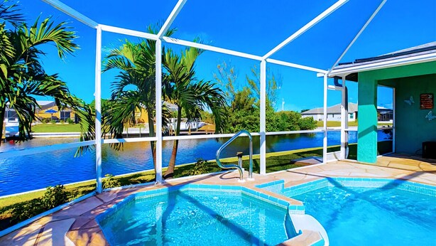 A swimming pool with a clear blue water, surrounded by palm trees and a covered area with a view of the water. - 30% Disc-2 Kg Mstrs, Golf, Fishing, BBQ, Pool, Spa (Cape Coral)