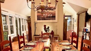 A dining room with a wooden table set for a meal, surrounded by chairs. - Secluded, Private Vacation Beach Home on Chappaquiddick Island, Walk To Beach. (Edgartown)
