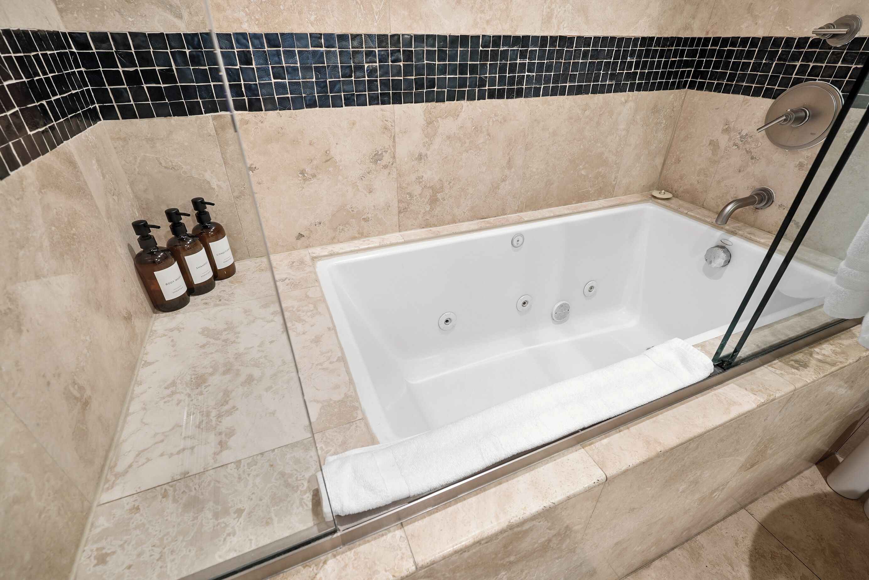 Une salle de bain moderne avec une baignoire sur pieds, une douche à parois de verre et un mur recouvert de carreaux.