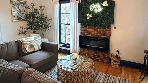 A living room with a brown sofa, a glass coffee table with flowers, a fireplace, and a 'Bride to be' sign. - Spacious West End Penthouse | Great for Groups (Portland)