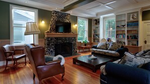 A living room with a stone fireplace, leather chairs, a sofa, and a bookshelf. - Very Private Rustic Home, sleeps 14, Huge Yard (Langley Township)