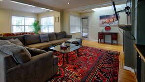 A spacious living room with a large sectional sofa, a coffee table, and a vibrant red rug. - Very Private Rustic Home, sleeps 14, Huge Yard (Langley Township)