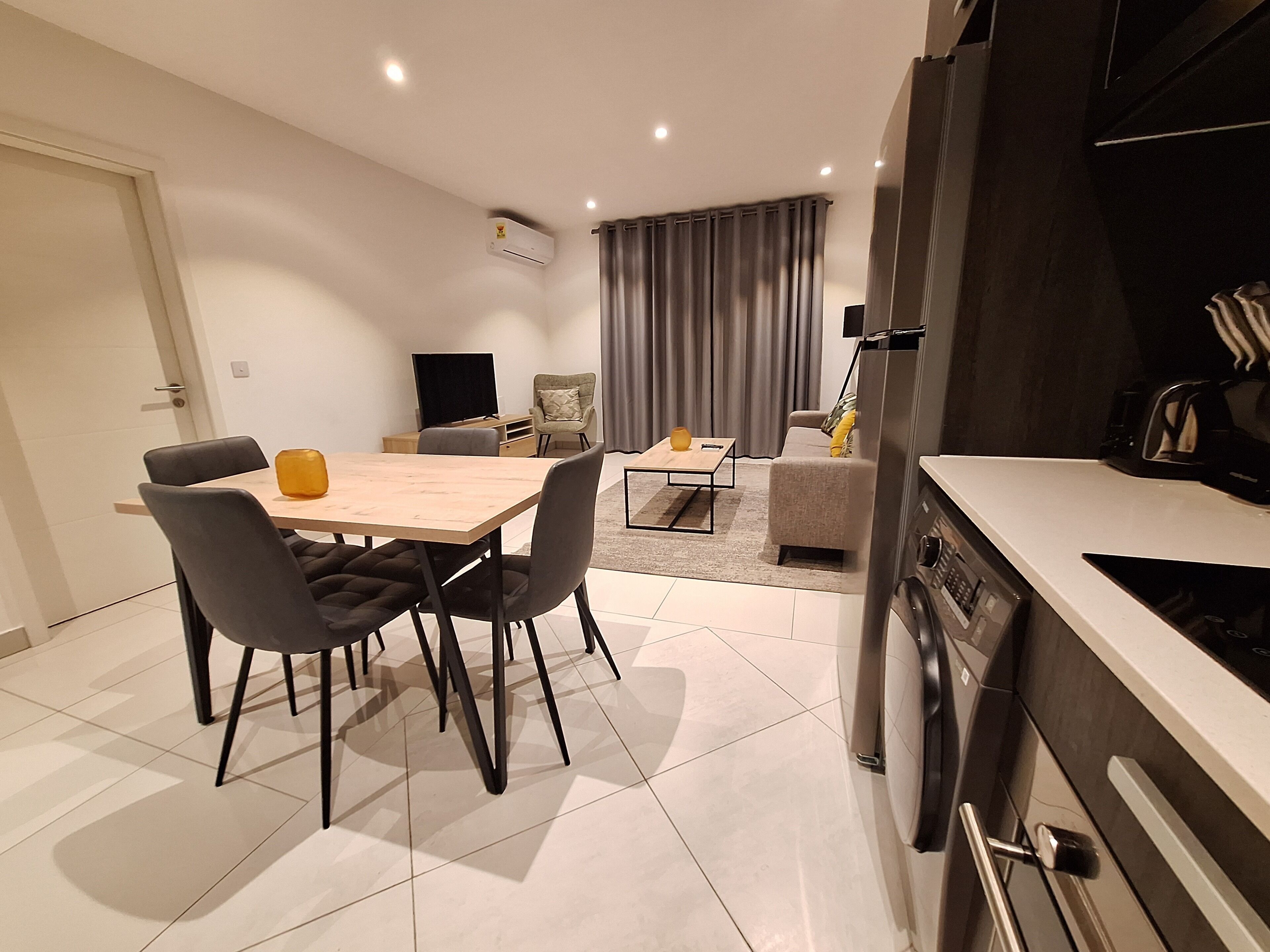 A modern kitchen with a built-in oven and a dining area with a table and chairs.