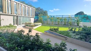 A modern building with large windows and a well-maintained garden area with a lawn and various plants. - The Lennox Abode (Accra)