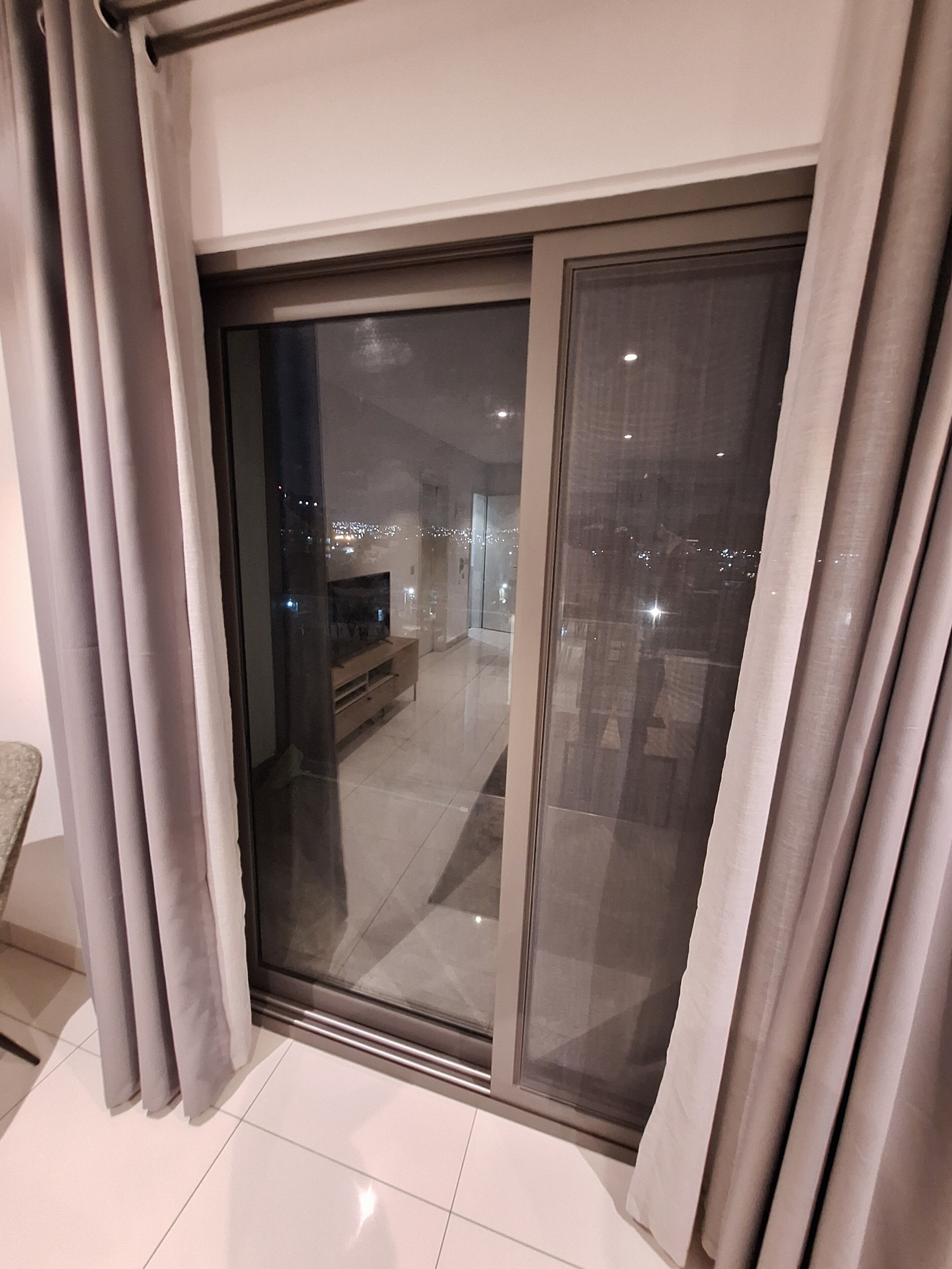 A modern living room with a large sliding glass door leading to an outdoor balcony.