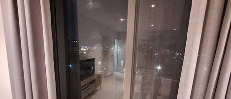 A modern living room with a large sliding glass door leading to an outdoor balcony.