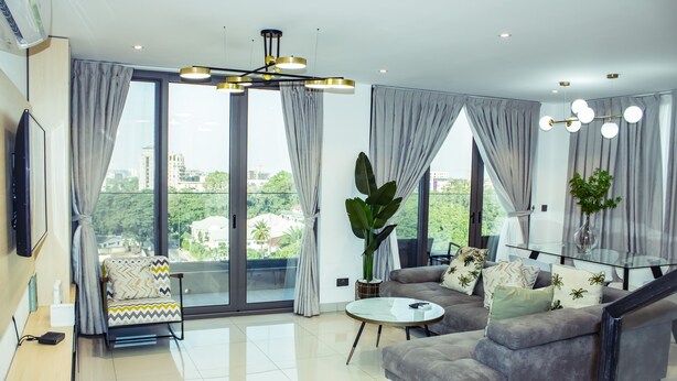 A modern living room with a sofa, a coffee table, and a TV. - The Lennox Abode (Accra)